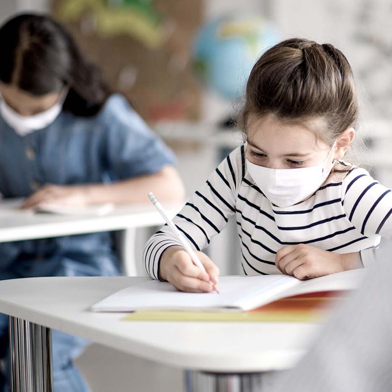 Student working in a classroom wearing a mask to help stop the spread of airborne viruses and bacteria.